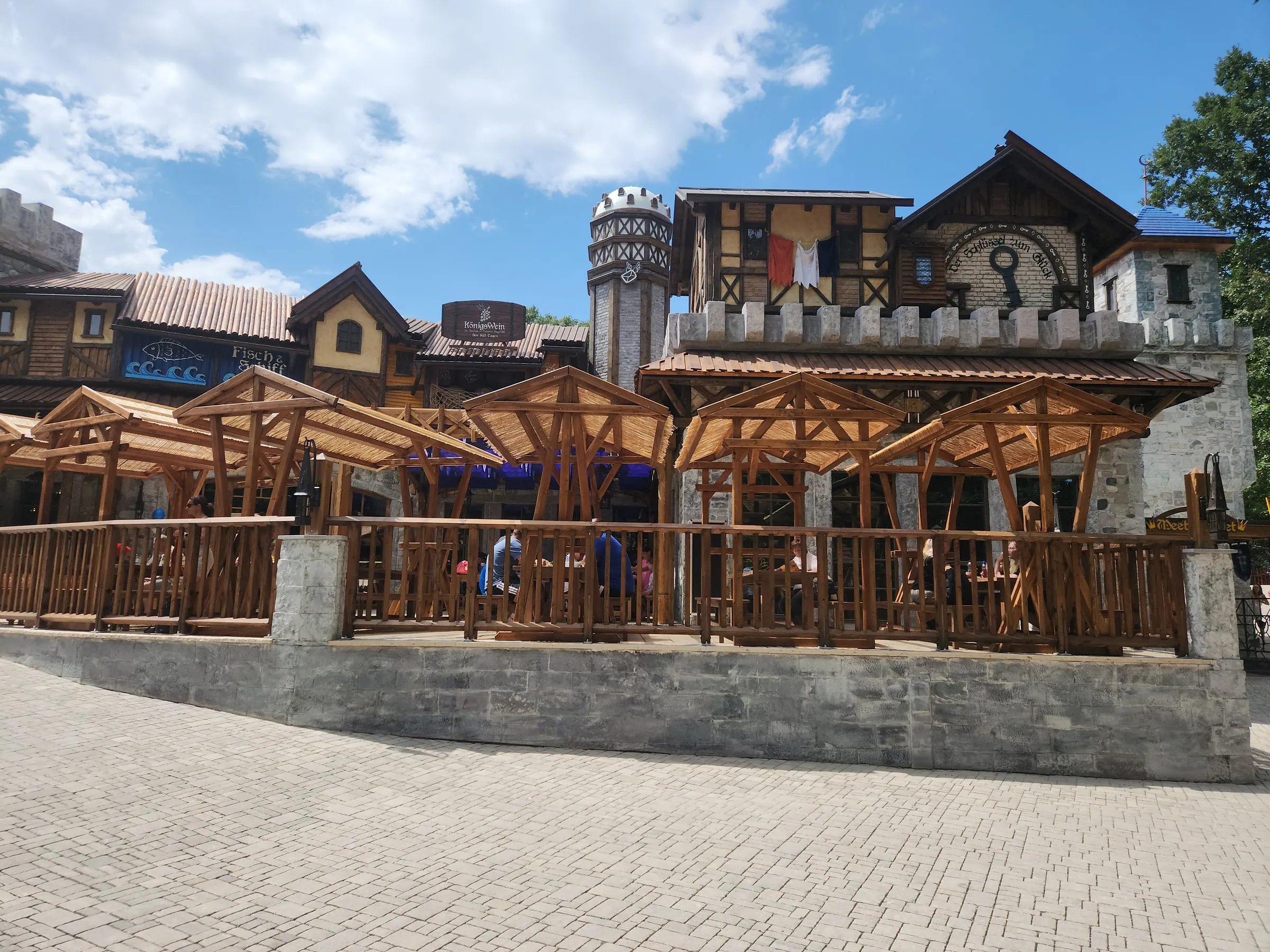 Außenanlage der Burgwelt mit Holzterrassen und steinernen Gebäuden