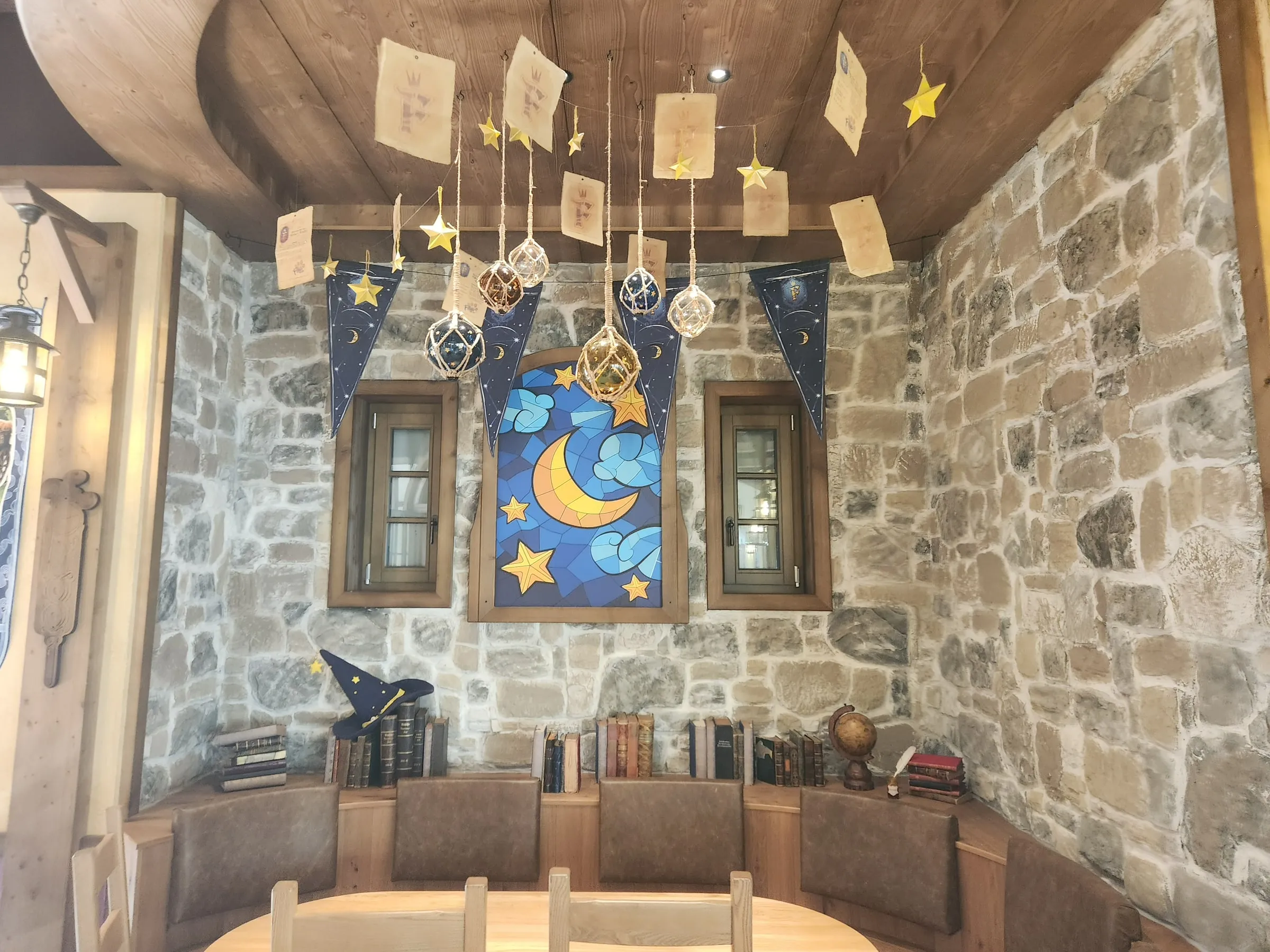 Innenraum mit Bruchsteinwänden, Holzdecke und stilisierter Mond-und-Sterne-Dekoration